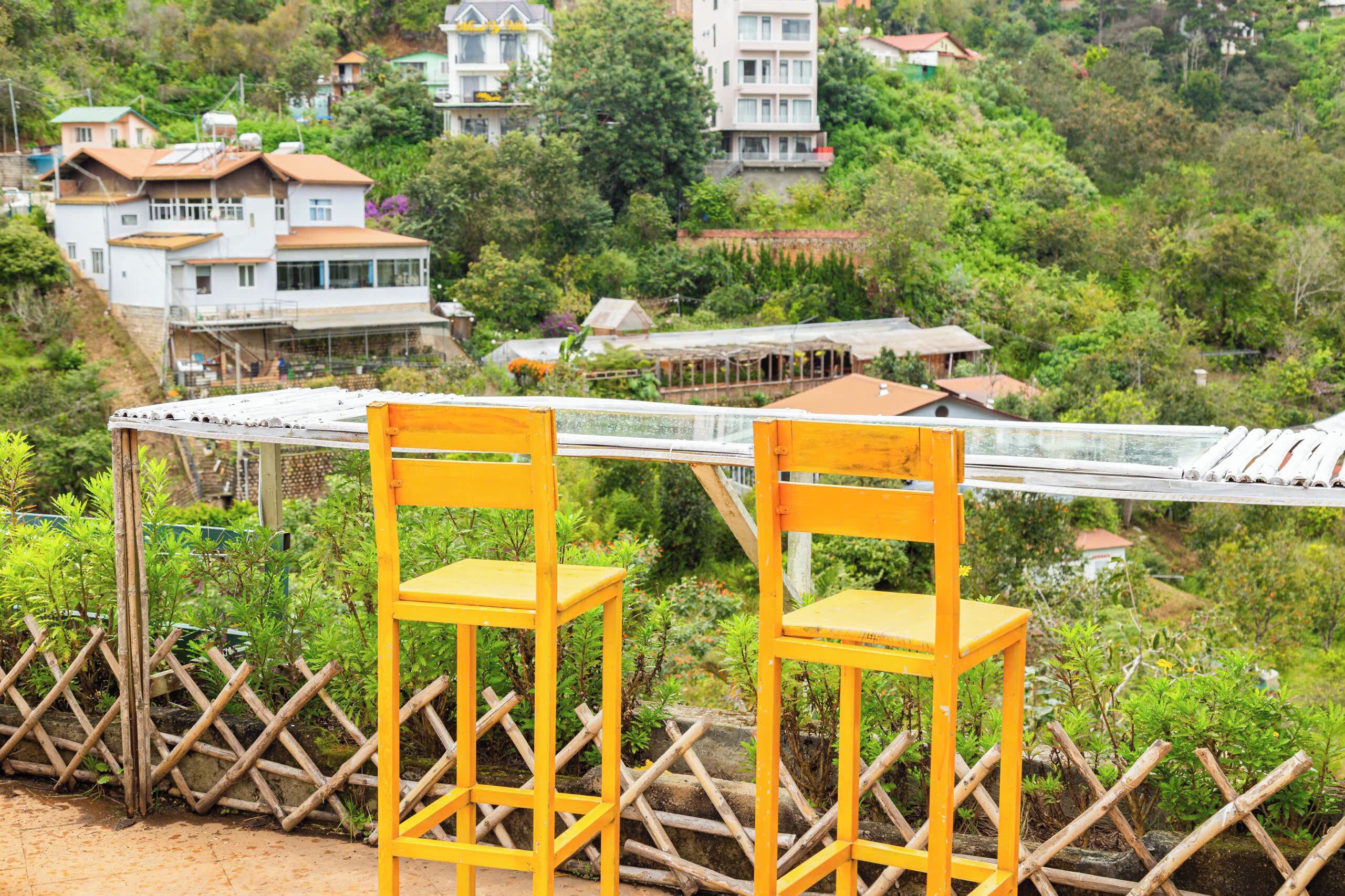 A view of a hillside with a wooden fence and two yellow chairs.