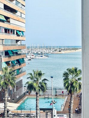 Un hôtel doté d  ’une piscine, offrant une vue sur le port de plaisance et bordé de palmiers.