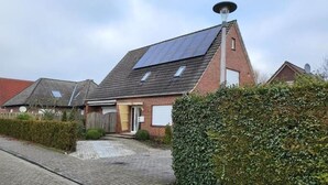 En bostadsbyggnad med ett sluttande tak, solpaneler och en fasad av tegel.