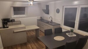 Ett kompakt kök med en matplats, en kaffemaskin och en klocka på väggen.