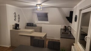 Ett kompakt kök med en matplats, ett litet fönster och en taklampa.