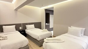 A modern hotel room with two beds, a seating area, and a wardrobe. - Grand Museum Pyramids Hotel (Giza)