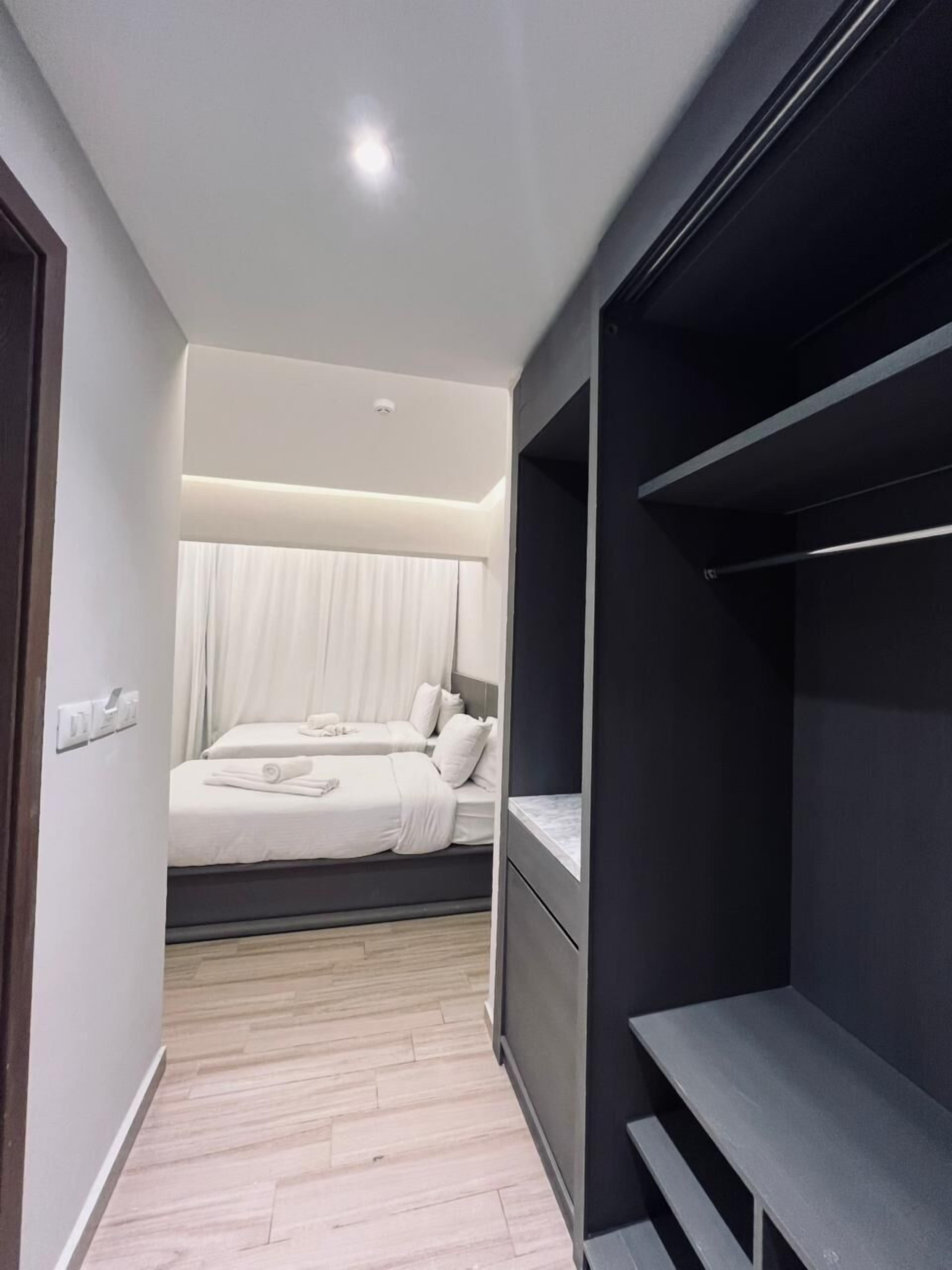 A modern hotel room with a bed, a bedside table, a wardrobe, and a walk-in closet.