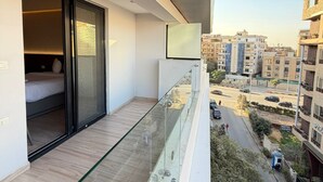 A balcony with a glass railing overlooking a street and buildings. - Grand Museum Pyramids Hotel (Giza)