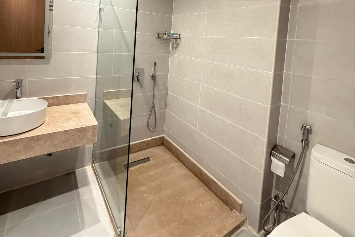A modern bathroom with a glass-enclosed shower, a sink with a marble countertop, and a toilet.