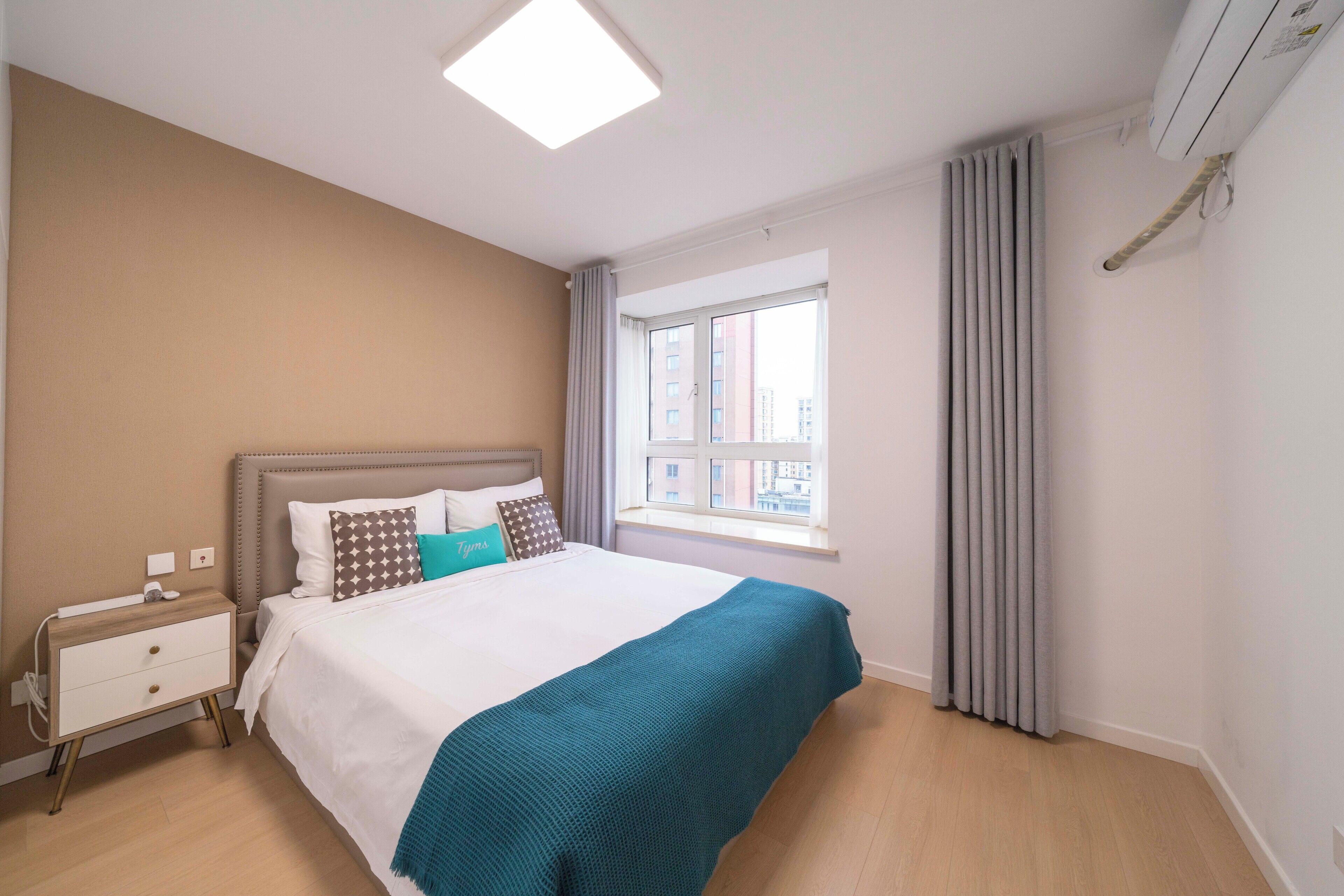 A bedroom with a bed, nightstand, window, and curtains.
