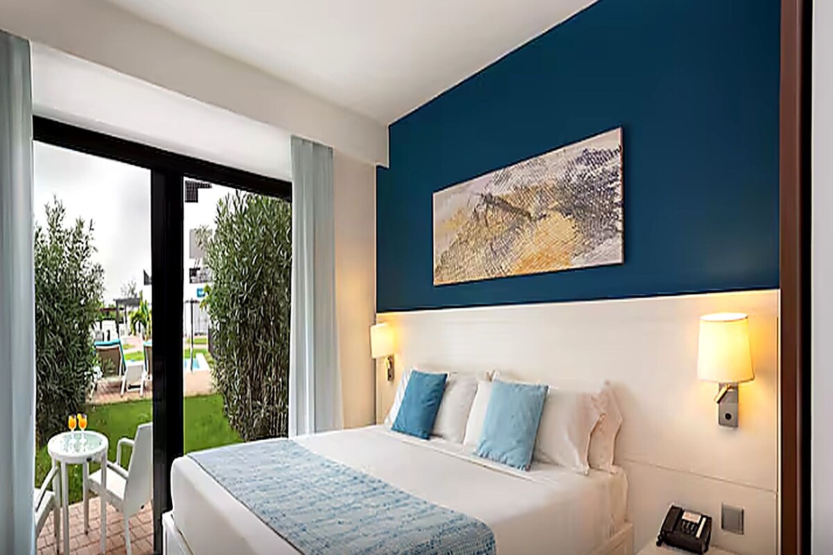 Une chambre d’hôtel avec un lit, un tableau au mur et une vue sur l’extérieur.