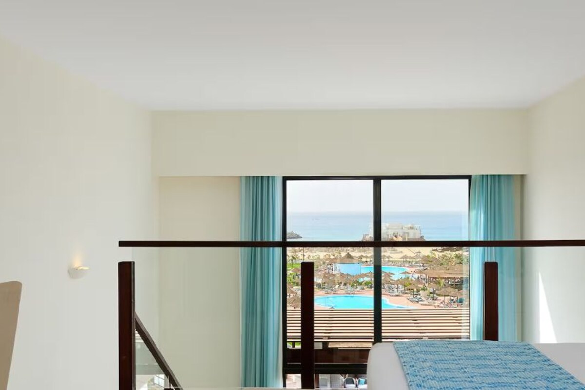 Une chambre d’hôtel avec un lit, une vue sur l’océan et un balcon.