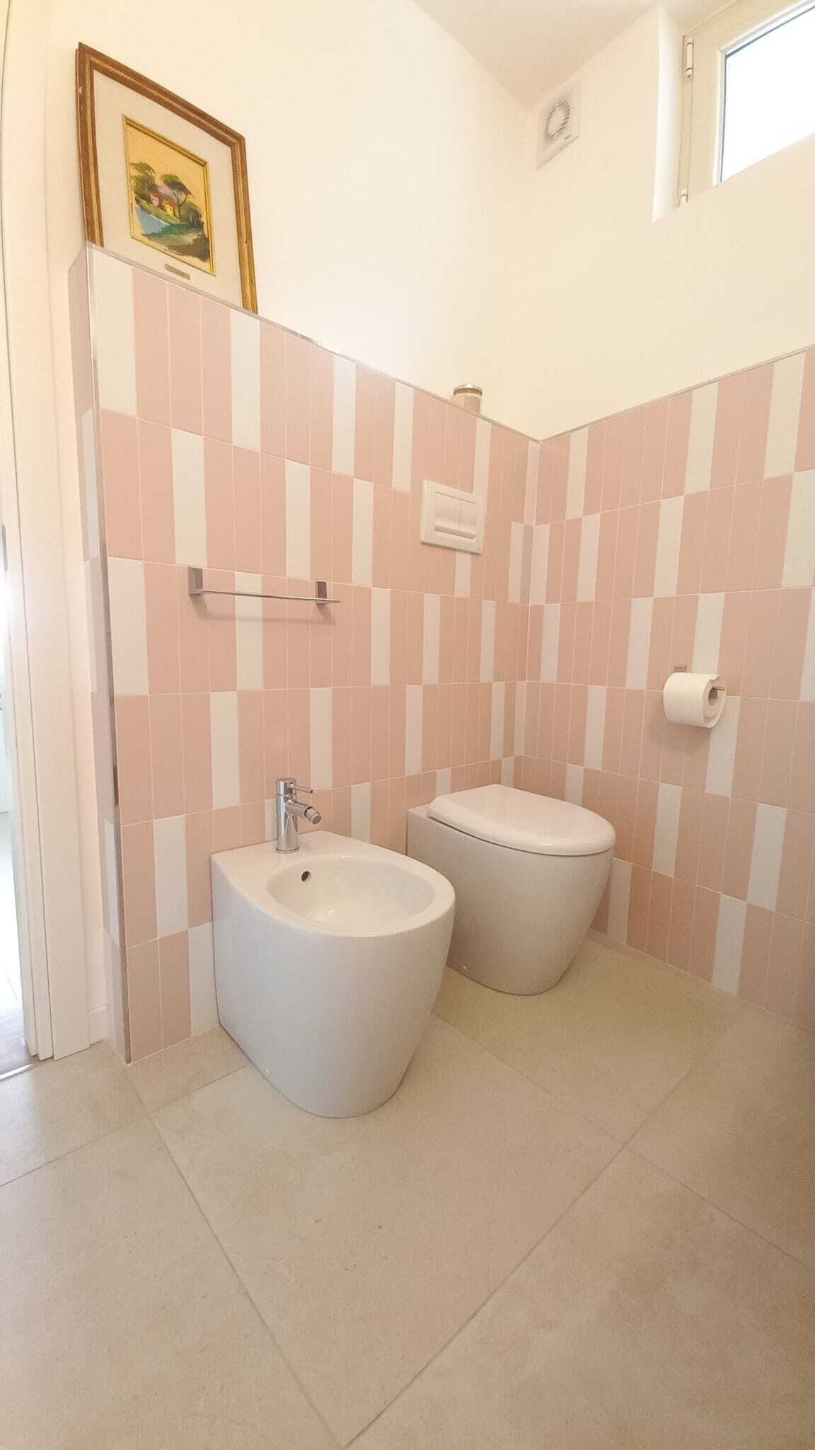 Une salle de bain avec deux toilettes, un lavabo et une douche.