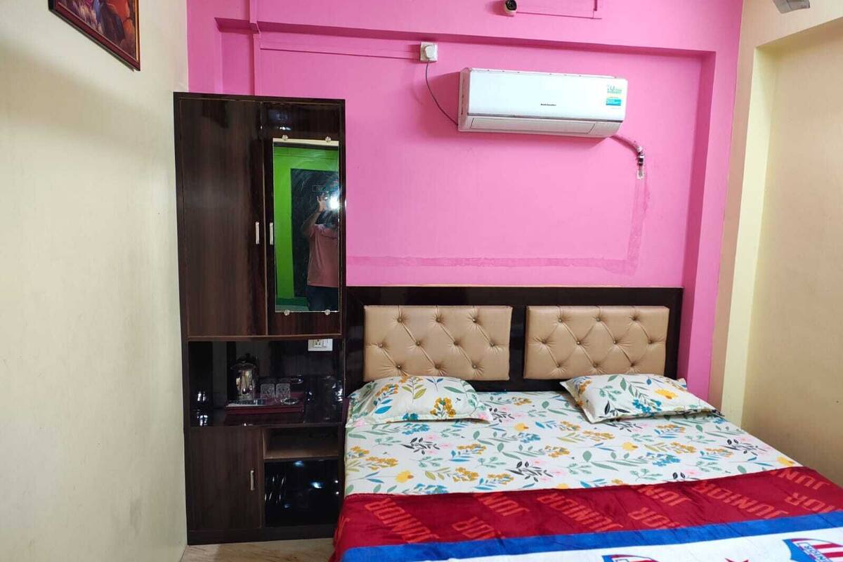 A bedroom with a bed, a wardrobe, a mirror, and an air conditioner.
