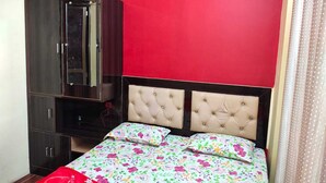 Une chambre à coucher avec un lit, une armoire et un mur rouge.
