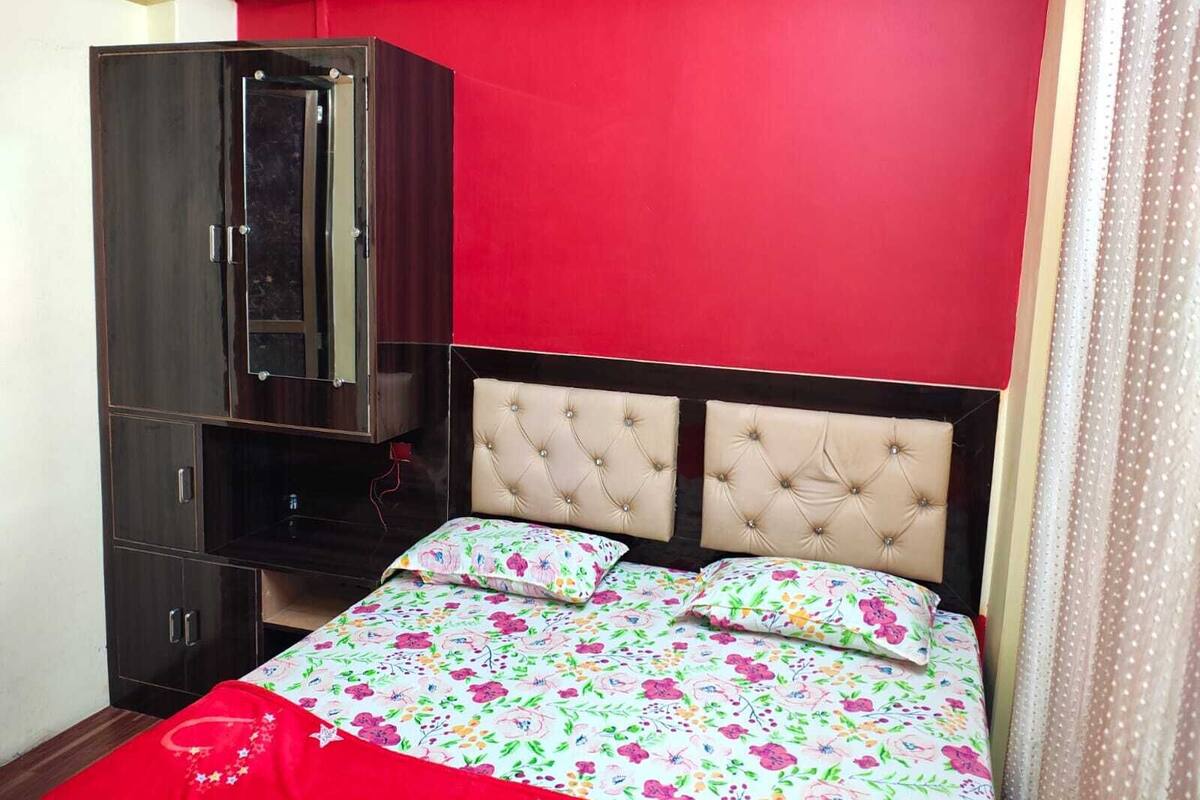 A bedroom with a bed, a wardrobe, and a red wall.