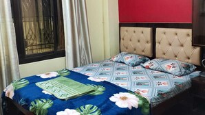 Une chambre à coucher avec un lit, des rideaux, un appareil de climatisation et un mur rouge.