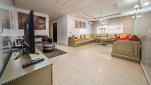 A spacious living area with a sofa set, a TV, and a remote control on a stand.