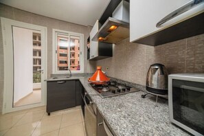 Una cocina moderna con estufa a gas, hervidor y microondas.