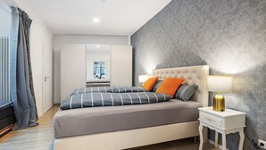 Une chambre à coucher moderne, avec un lit, une table de chevet et une vue sur une autre pièce.