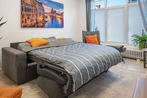 Une chambre à coucher moderne avec un lit, une fenêtre, un radiateur et une plante.