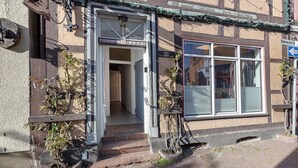 Un bâtiment à la façade traditionnelle, avec une entrée bien visible et une fenêtre équipée de stores.