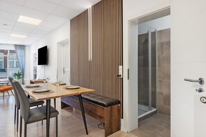 Un intérieur moderne avec un séparateur en bois, un banc, une table à manger avec des chaises et un espace douche.