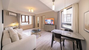 Une chambre d’hôtel moderne équipée d’un canapé, d’une table à manger et d’un téléviseur.