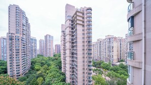Un immeuble résidentiel de grande hauteur, doté de nombreux balcons, et un vaste parc verdoyant en premier plan.