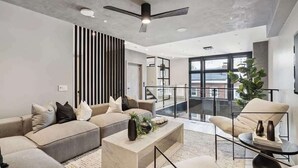 A modern living room with a sofa set, a coffee table, and a chair. There is a ceiling fan, a large window, and a plant. - Where Rock & Roll Royalty Crash - Hot Tub & More (Philadelphia)