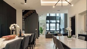 A modern kitchen with a marble countertop, a dining area with grey chairs, and a staircase leading to a loft. - Where Rock & Roll Royalty Crash - Hot Tub & More (Philadelphia)