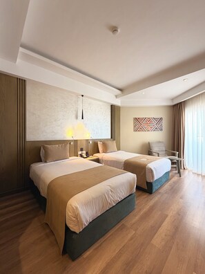 Une chambre d’hôtel avec deux lits, un bureau, une chaise, une lampe et un tableau au mur.