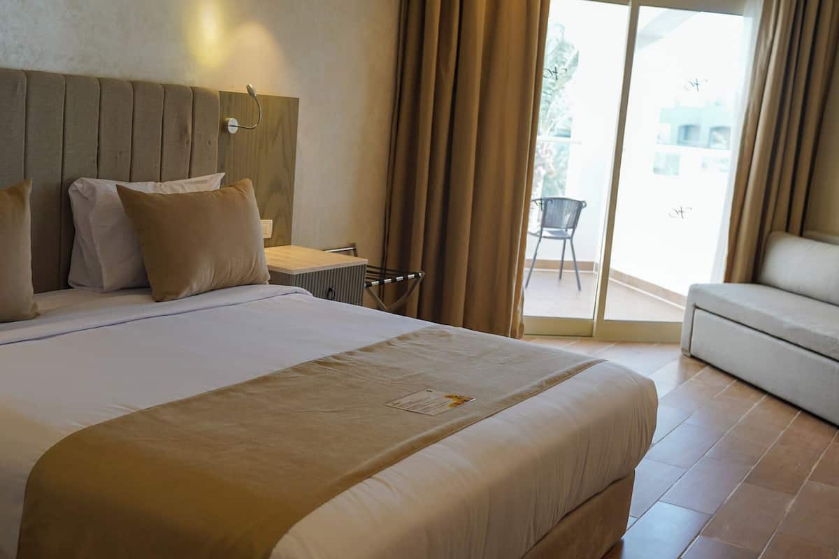 Une chambre d’hôtel avec un grand lit, un canapé, un bureau et une vue sur l’extérieur.