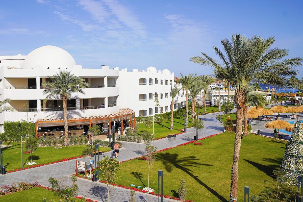 Un hôtel à plusieurs étages doté d’une cour intérieure, de palmiers et d’un espace piscine.