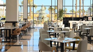 Un'ampia sala da pranzo con soffitti alti, grandi finestre e lampade a sospensione moderne.