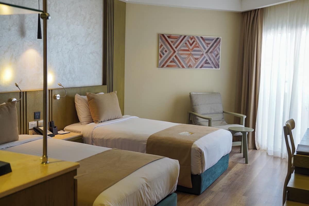 Une chambre d’hôtel avec deux lits, un bureau, une chaise et une petite table.