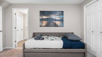 A bedroom with a bed, a painting, and a door.