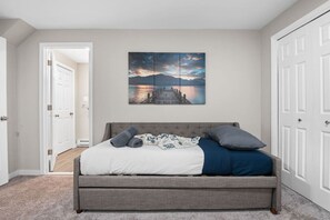 A bedroom with a bed, a painting, and a door.