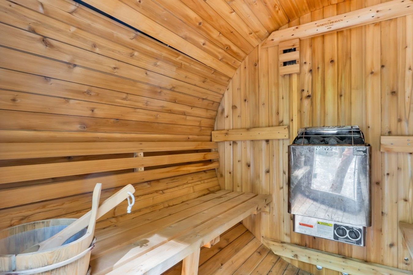 A sauna room with wooden walls, a bench, and a sauna heater.