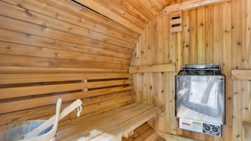 A sauna room with wooden walls, a bench, and a sauna heater.