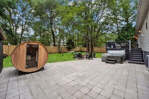 A circular wooden structure, possibly a sauna, on a patio with a fire pit and outdoor furniture. - Lake House: Hottub, Sauna, Firepit, Games! (Albrightsville)