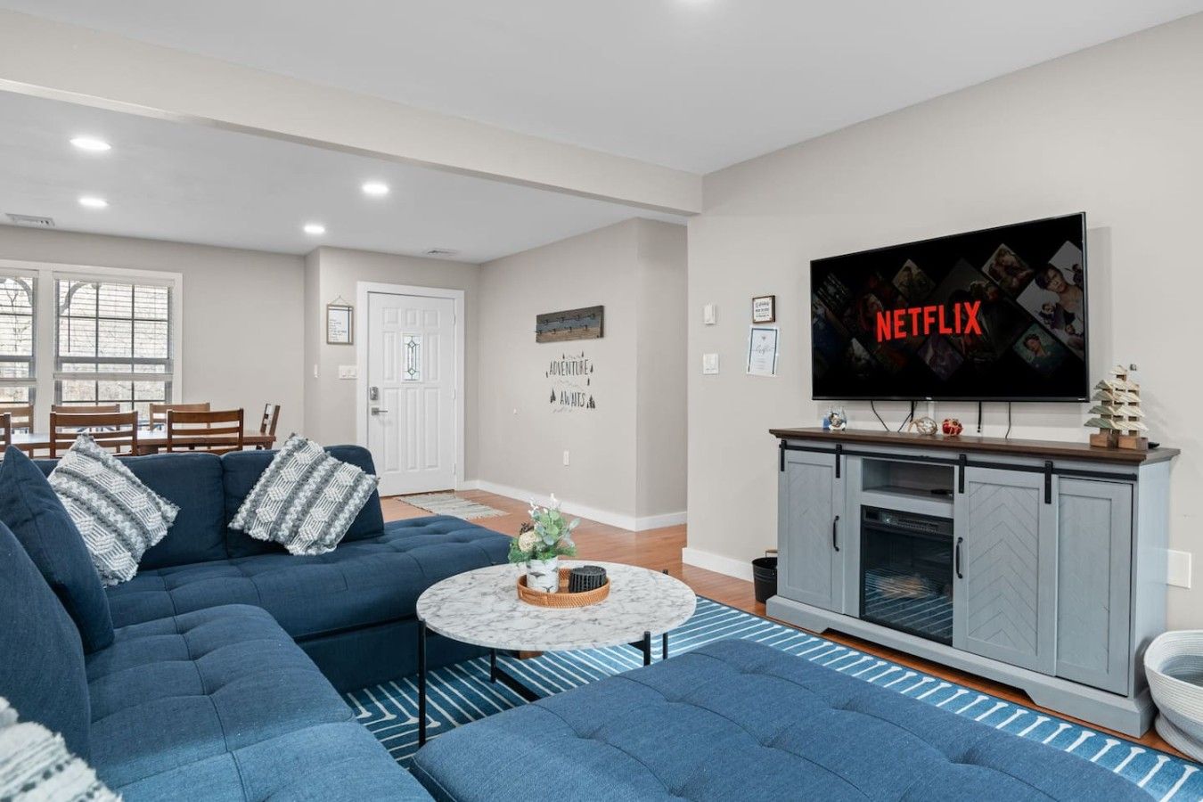 A living room with a blue sofa, a coffee table, and a TV displaying the Netflix logo.