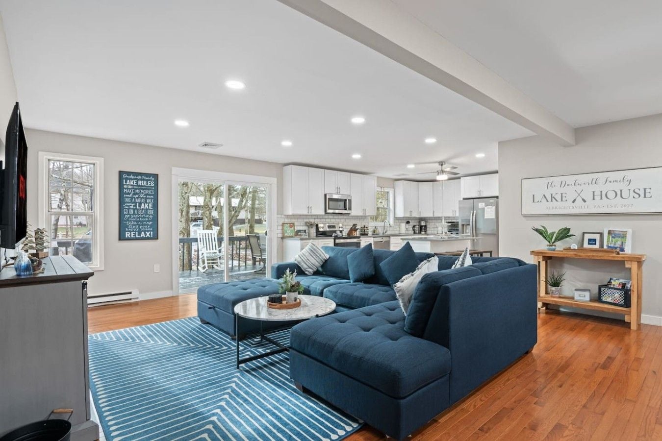 A modern living room with a sectional sofa, a coffee table, and a view of the kitchen.