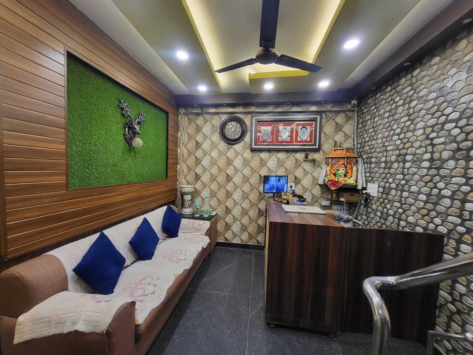 Un área de recepción con un mostrador de madera, una pared verde con una planta decorativa, un reloj y un pequeño altar.