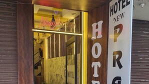 The entrance of Hotel Pratap with a neon sign, wooden door, and a green mat. - Hotel New Pratap (Haridwar)
