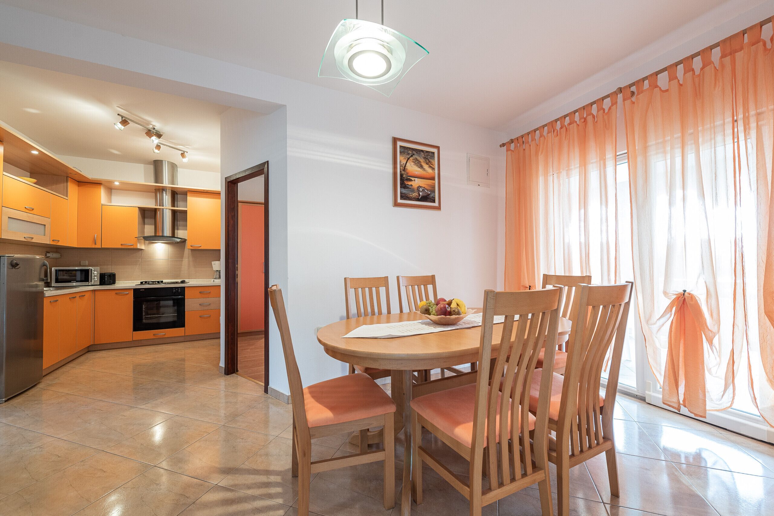 A modern kitchen with a dining area, featuring a round table with chairs, a microwave, and a stove.