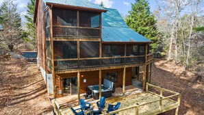 Een chalet van hout met twee verdiepingen, een balkon, een terras buiten en een jacuzzi.