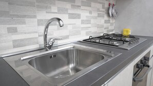 A modern kitchen with a stainless steel sink, a gas stove, and a tiled backsplash. - Maison 54 - Canneto Lake (Brescia)