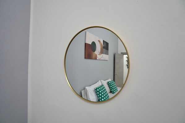 A circular mirror with a gold frame on a plain wall.