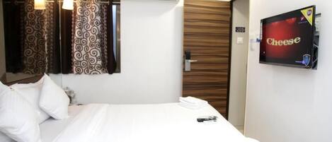 A hotel room with a bed, white curtains, a mounted TV screen displaying 'Cheese', and a door with the number '205'.