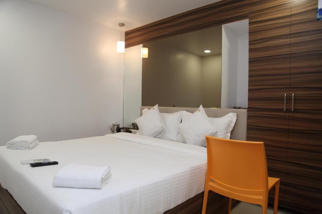Ein Hotelzimmer mit Bett, weißen Laken, einem Holzschrank und einem Spiegel.