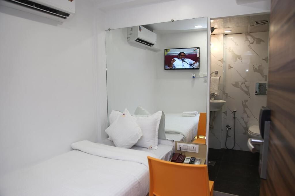 Ein Hotelzimmer mit Bett, Sessel, Fernseher und Badezimmer mit Dusche und Toilette.