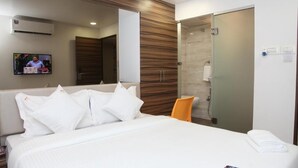 Une chambre d’hôtel avec un lit, une télévision, une douche et un miroir.