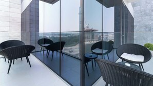 A modern balcony with large glass doors, black wicker furniture, and a view of a construction site.